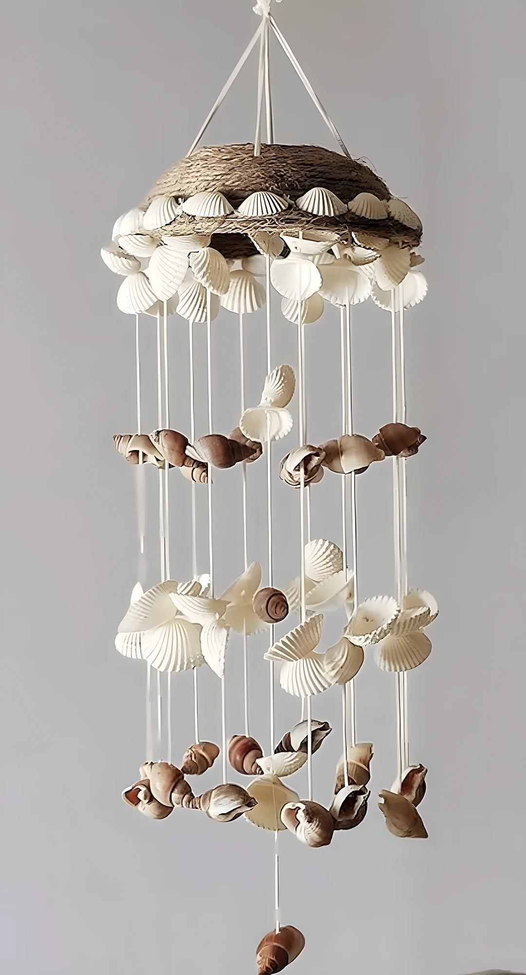 Hanging shell dome with ribbon, circular base, and layered shells; intermediate craft using threading and knotting.