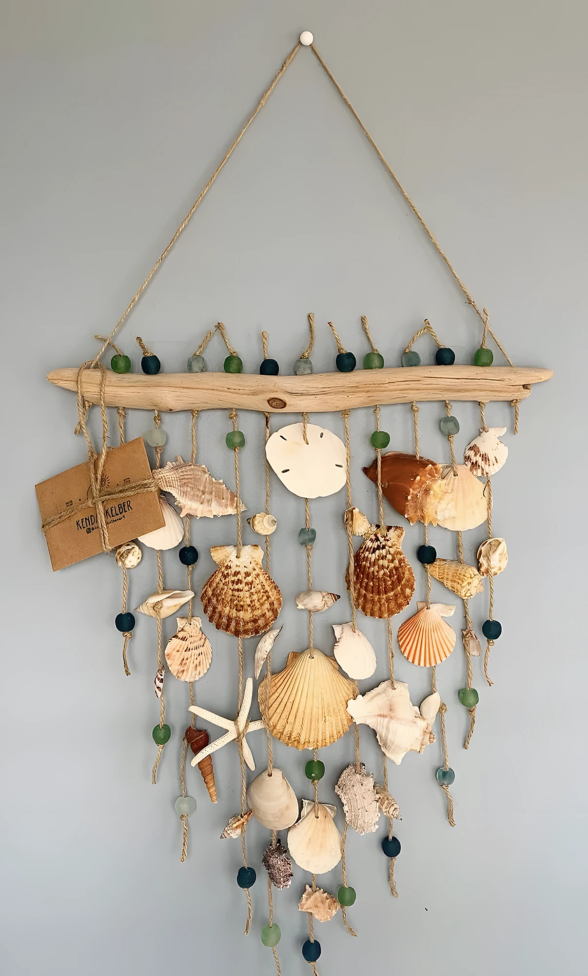 Handmade coastal wall hanging with driftwood, shells, twine, and beads; beginner to intermediate knotting and drilling.