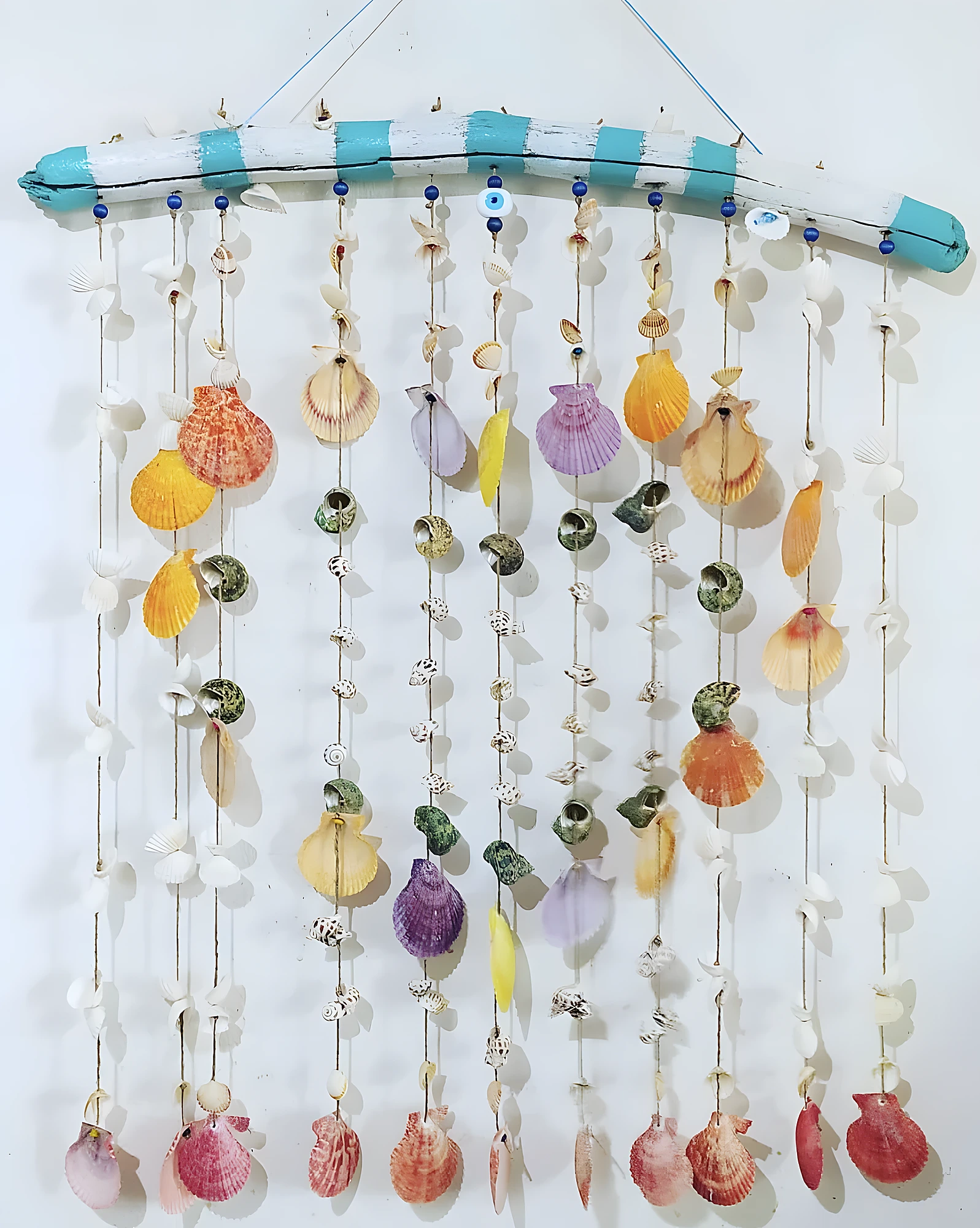 Vertical shell curtain on painted driftwood with many hanging strands, advanced beach-inspired craft installation.