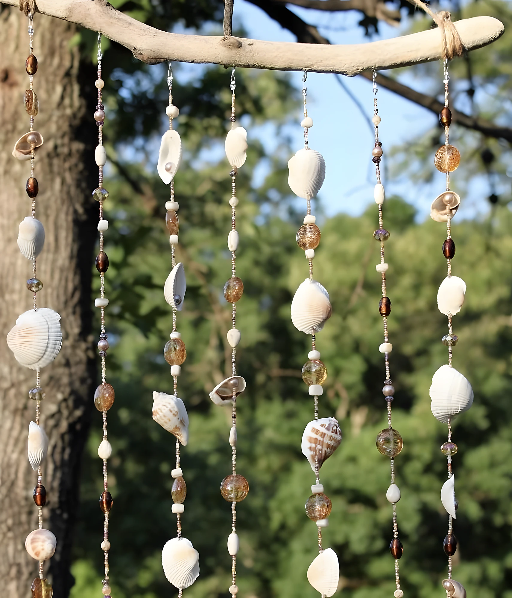 Elegant seaside wind chime with driftwood, seed beads, and mixed shells; moderate difficulty with delicate stringing.